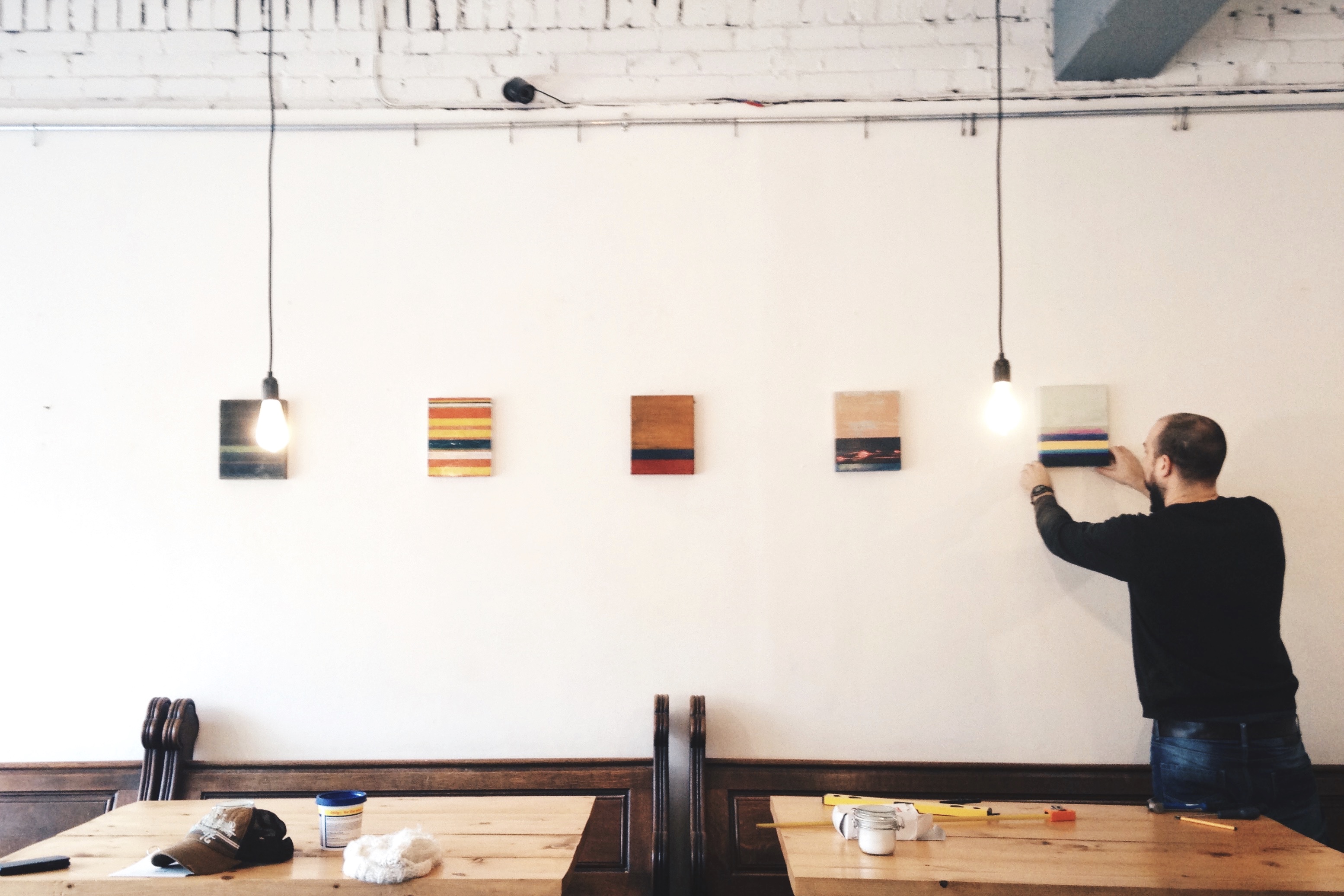 Tom Harman installs abstract paintings at Little Man Coffee Co., Cardiff. Photograph: Rhys Tranter.